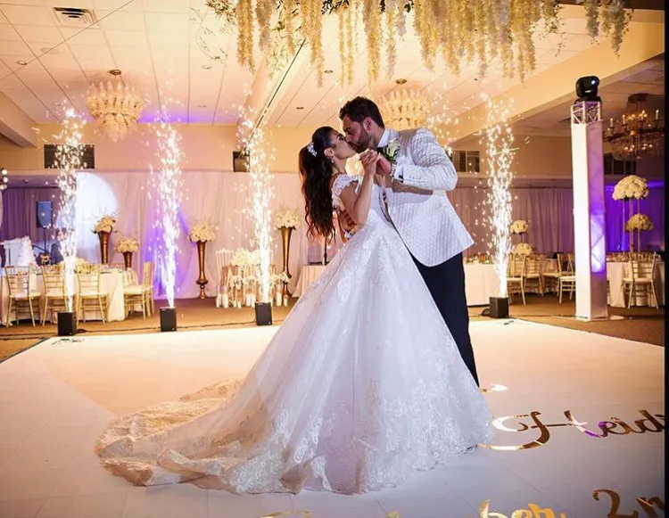 A bride and groom share their first dance beneath a hanging floral installation as sparkler fountains light the Palace Center ballroom