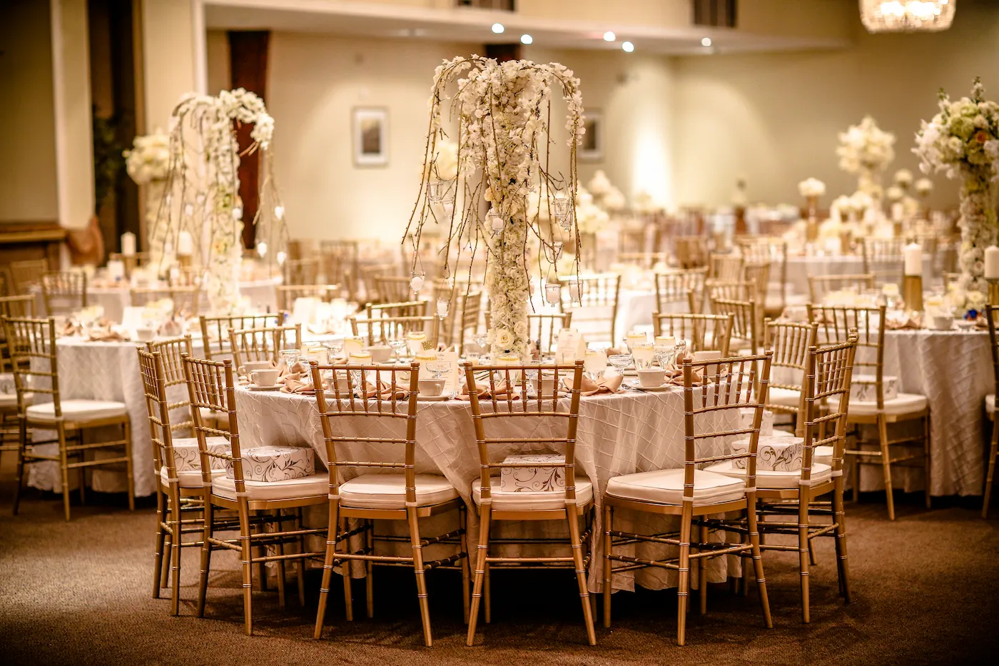 Tables set with gold chiavari chairs and floral centerpieces at The Palace Center